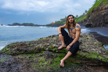 European man with drawings on his body walks among the rocks