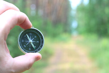 Old classic navigation compass in hand on natural background as symbol of tourism with compass,...