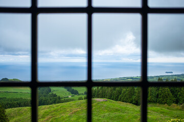 View from a window of the landscape of São Miguel Island and the Ocean with the Islet of Vila Franca do Campo on the background, Azores, Portugal.