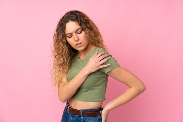 Young blonde woman with curly hair isolated on pink background suffering from pain in shoulder for having made an effort