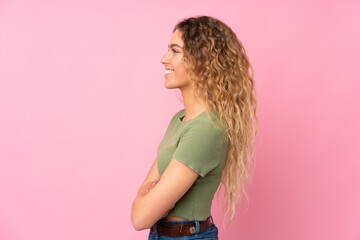 Young blonde woman with curly hair isolated on pink background in lateral position