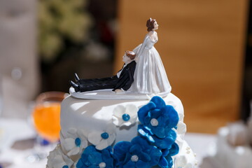 Funny figurines suite at a luxury wedding white cake decorated with fresh flowers.