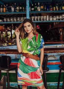 Beautiful short-haired model posing for photos in a restaurant. wearing colorful dress. 