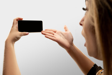 Shocked, astonished. Close up female hands holding smartphone with blank screen during online watching of popular sport matches, championships. Copyspace for ad. Devices, gadgets, technologies concept