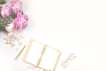 Female diary, golden pen and jewelry, pink peonies on a white background. Copy space