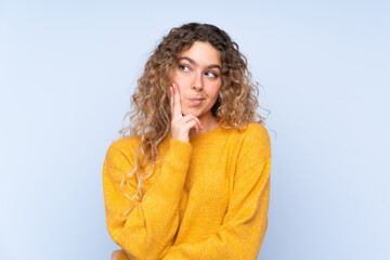 Young blonde woman with curly hair isolated on blue background Looking front