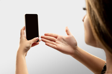 Gesturing, asking. Close up female hands holding smartphone with blank screen during online watching of popular sport matches, championships. Copyspace for ad. Devices, gadgets, technologies concept.