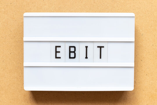 Lightbox with word EBIT (Abbreviation of Earnings Before Interest and Taxes) on wood background