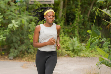 young black  runner girl enjoying outdoors jogging workout - young attractive and fit African American woman running at countryside road in sport practice concept