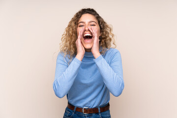 Young blonde woman with curly hair wearing a turtleneck sweater isolated on beige background...