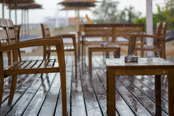 It's raining on the beach bar. The wooden salt shaker and wooden table are completely wet as is the ashtray on the table. The rain fell suddenly and the guests left.