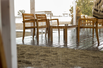 Focus on wet wooden tables and chairs in a beach cafe. The weather was easily bad and it rained suddenly.