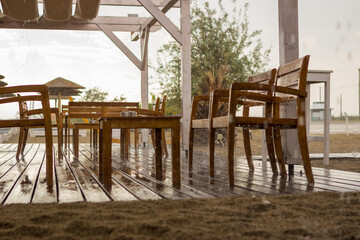 The weather on the beach is very bad. It is raining hard and the wooden chairs are wet. The guests left.