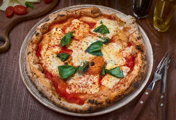 High Angle View of Fresh Baked Margherita Pizza Topped with Tomatoes, Cheese and Fresh Basil on Wooden table