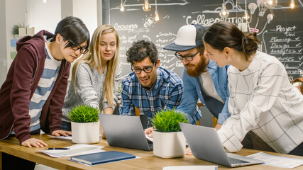 Team Meeting of Developers, They Lean on the Table and Look at the Results Shown on the Laptop. Creative Young People in Stylish Office Environment.