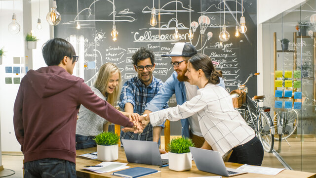 Diverse Team of Creative Developers Make Building Successful Partnership Gesture with teir Hands. Happy Succesful Young People Stylishly Dressed in the Trendy Office Environment.