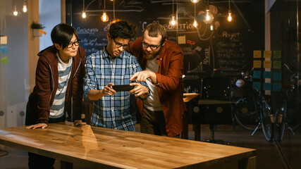 Great Concept For Augmented Reality Mock-up. Three Young Developers Look at Augmented Reality Through Smarthpone. They're Working on the New Virtual Reality Game.