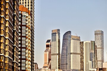 Residential skyscrapers on bright clear blue sky background. Commercial real estate and apartments market development. Modern urban architecture in city downtown. Modern residential city district.
