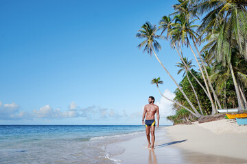 Young bearded man on the tropical sand beach.