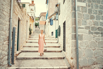 Fototapeta na wymiar Traveling by Europe. Happy young woman in elegant dress walking by streets in Split, Croatia.