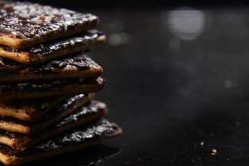 dry bread with the basis of wheat with a mixture of chocolate, sugar and grated coconut. snacks with sweet and salty taste. wafer with a dark background