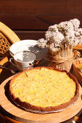 Tea party on sunny patio chatting. Apple Tart and vase of flowers on the table.