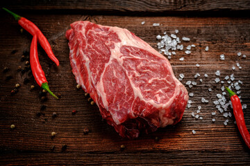 Raw Chuck Eye Roll beef Steak on a rustic wooden background with seasonings