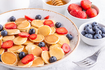 Tiny pancakes with strawberries and blueberries for breakfast.