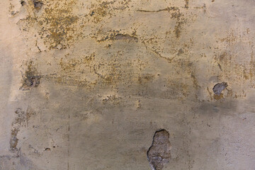 Grunge plastered wall with cracks. Dirty and weathered cracked stucco on the wall of old building. Retro concept. Abstract texture or background.