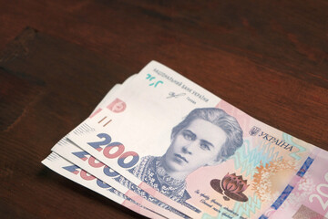 New Ukrainian paper money. Two hundred hryvnia notes on brown wooden background. Cash concept. Close up shot.