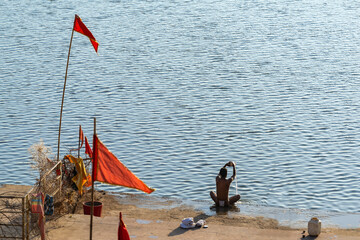 Indian man bathing and making offerings at the Narmada River in Bandrabhan, Madhya Pradesh, India