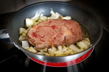 fresh cooking at home - grilled beefsteak with onions in olive oil in a hot pan