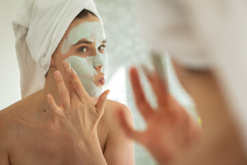 Woman applying face pack while looking in the mirror