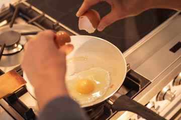 Mid section of woman cooking eggs in the kitchen