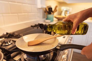 Mid section of woman pouring oil on frying pan