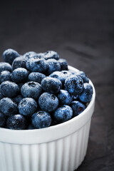 Organic blueberries in a white Cup on a black Board.