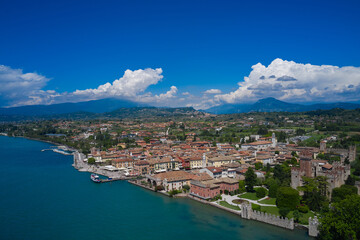 Fototapeta na wymiar Lazise, Lake Garda, Italy. Aerial view of the historic part of Scaliger Castle of Lazise in the background cumulus clouds in the blue sky