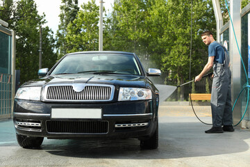 A man washes a car in a manual car wash. Clear car