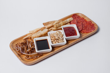 beer appetizers set with peanuts, salami, toasts, and cheese on wooden board isolated