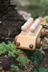 Children's wooden toys. Children wooden car with passengers outdoors. Natural wood construction set.