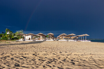 The dark blue sky is above the beach bar by the sea. It's like a storm. The beach is empty and there are no people.