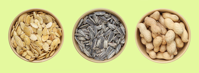 Three types of snacks in brown bowl: Sunflower seeds, peanuts in shell, salty pumpkin seeds. Top view of different food samples