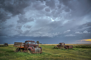Obraz premium Old, abandoned vehicles on the Great Plains as Severe Weather Approaches