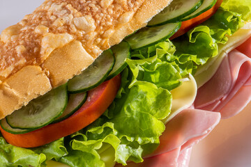 

Natural sandwich with baguette bread. Cheese, ham, lettuce, tomato and cucumber.