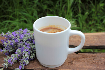 Cup of coffee with milk or cappuccino and lavender flowers on wooden board in summer garden. Enjoying morning coffee. Top view, copy space. Selective focus