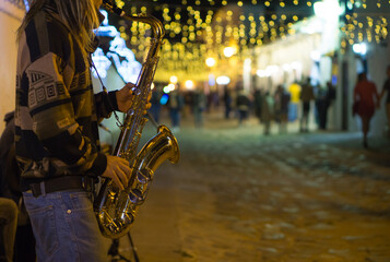 Músico tocando saxofón en calle iluminada de noche