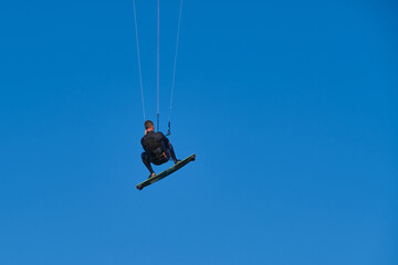 Naklejka na ściany i meble Kitesurfer in wetsuit in the jump on a background of blue sky