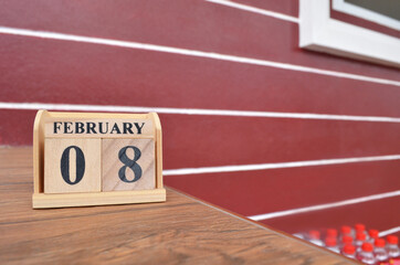 February 8, Number cube with wooden table beside the wall.