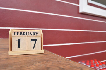 February 17, Number cube with wooden table beside the wall.