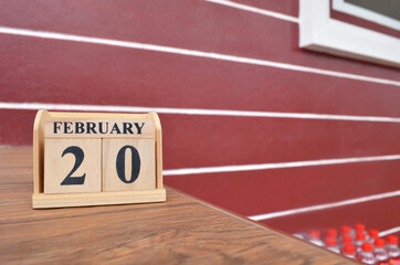 February 20, Number cube with wooden table beside the wall.